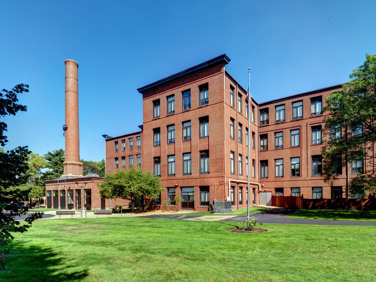 Exterior view of Robinson Cuticura Mill Apartments surrounded by green lawns
