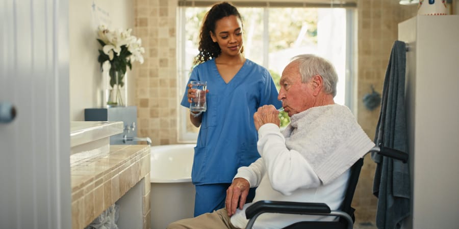 Care staff assisting a senior resident in a bathroom