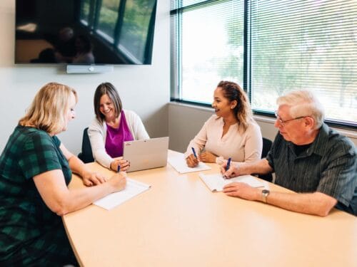 Four people engaged in a meeting around a table.