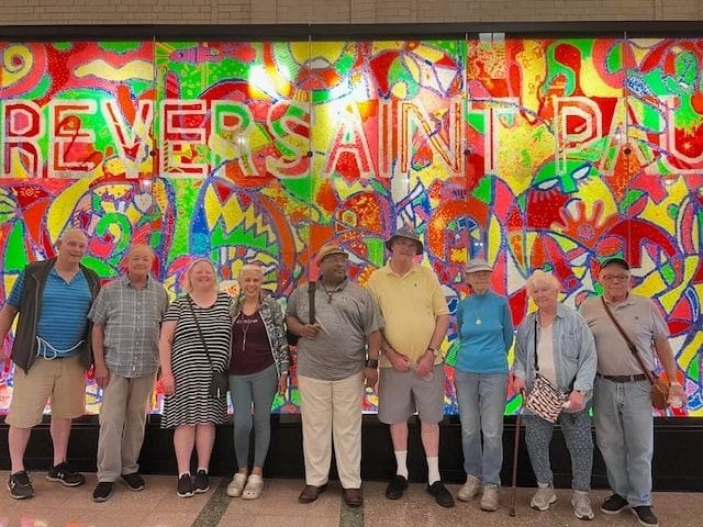Group of residents posing in front of a colorful mural