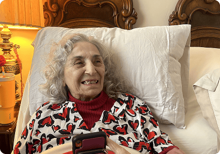 Senior woman smiling in a cozy bedroom setting.