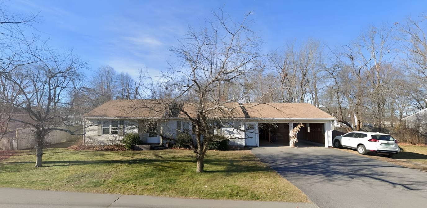 Exterior view of a residential building with trees and a driveway