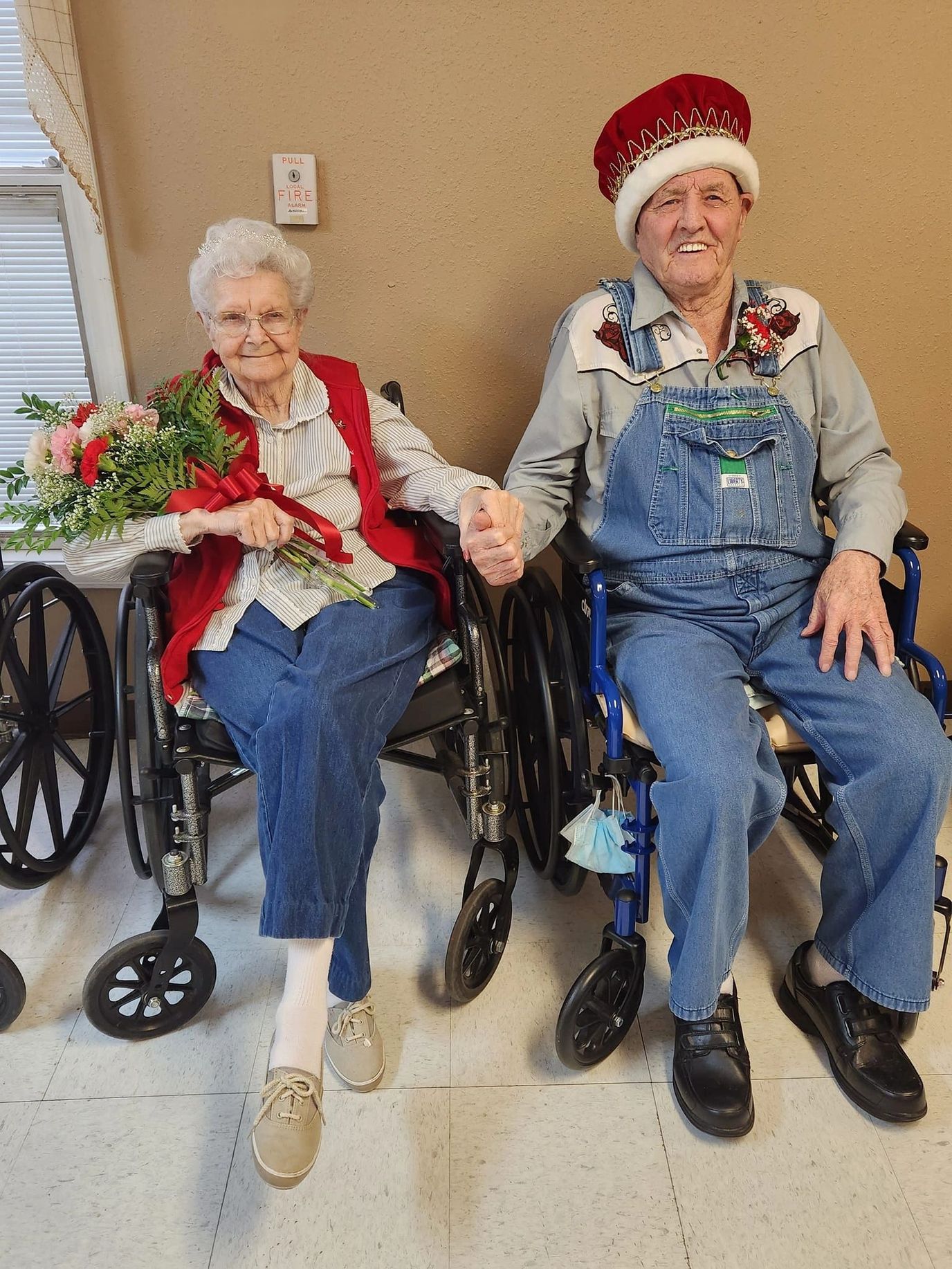 Elderly couple holding hands in a common area.