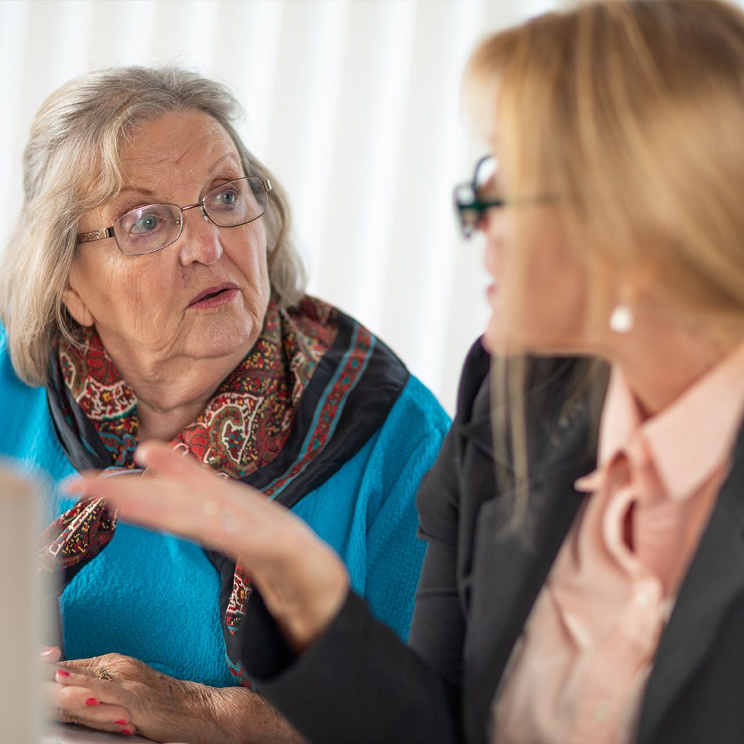 Elderly woman conversing with a caregiver