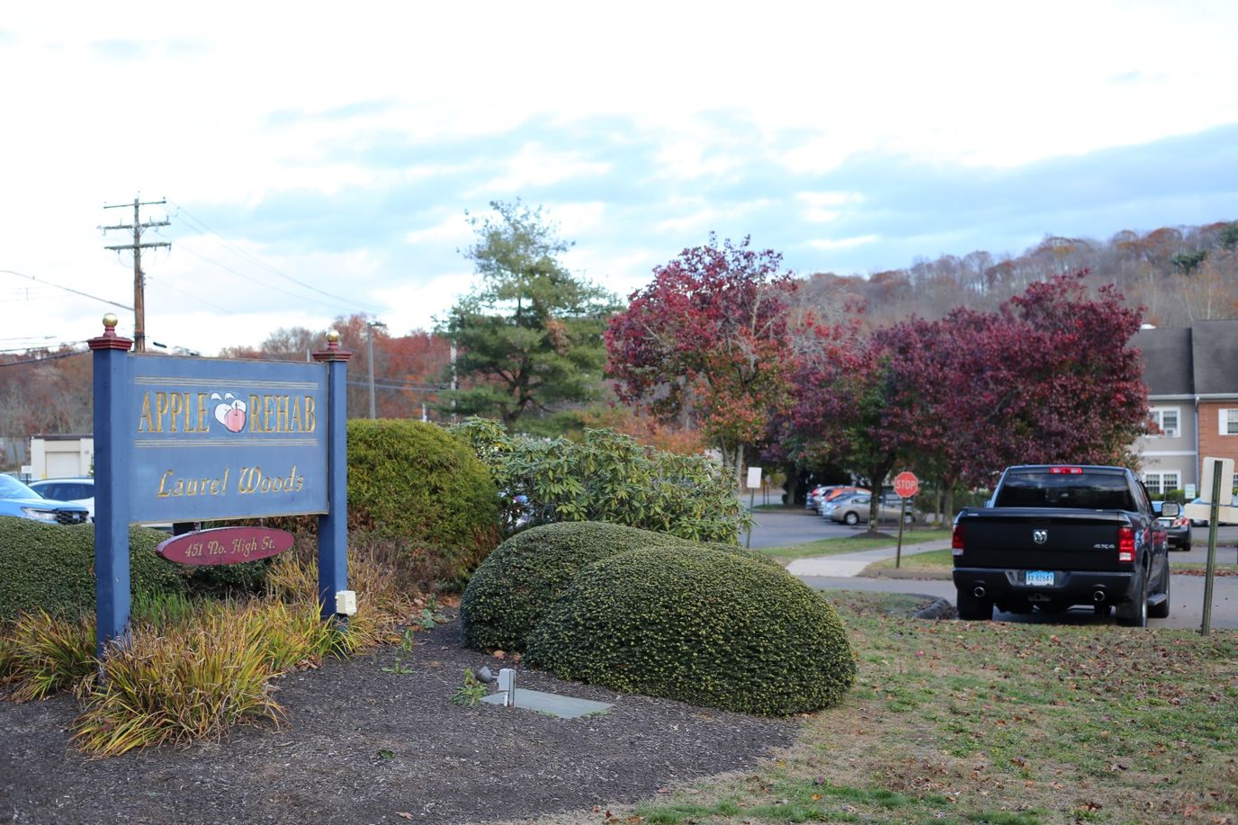 Outdoor view of Apple Rehab Laurel Woods sign and landscaping