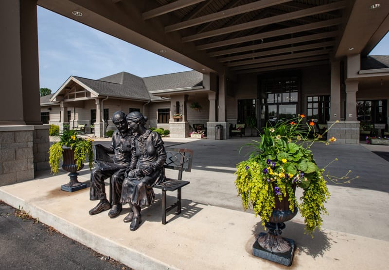 Statue of an elderly couple on a bench outside the facility