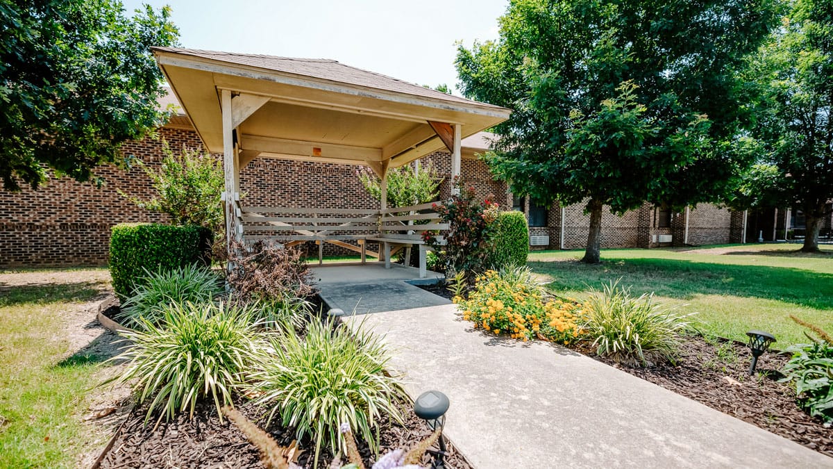 Pathway leading to a shaded seating area with flowers