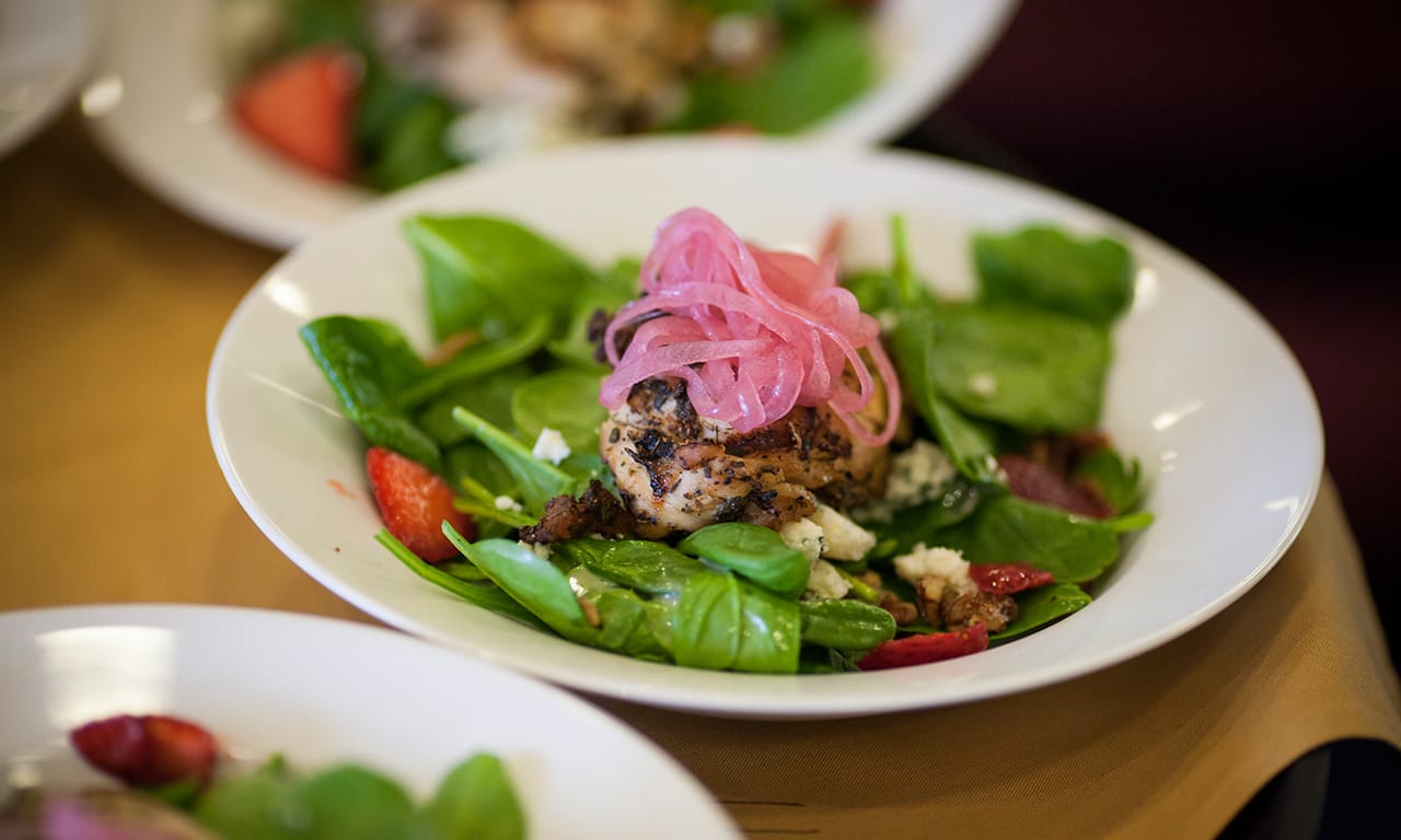 A beautifully arranged salad with grilled chicken and toppings