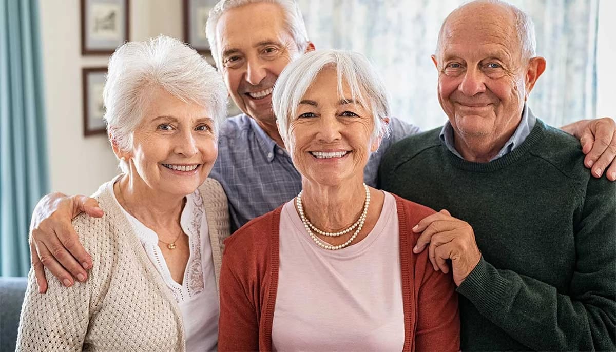 Four smiling seniors in a cozy indoor setting.