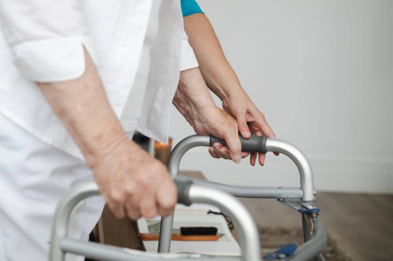 Hands of a caregiver assisting a resident with a walker.