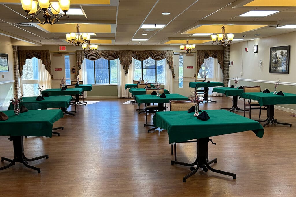 Dining area with tables set and green tablecloths.