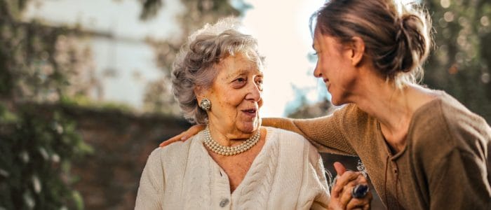 A resident enjoying conversation with a staff member outdoors