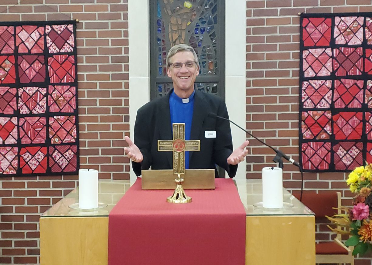 A clergy member speaking at a ceremony in a chapel