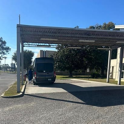 Plaza Community Living Center, Nursing Home in Pascagoula, MS — Facility van under covered area with staff assisting