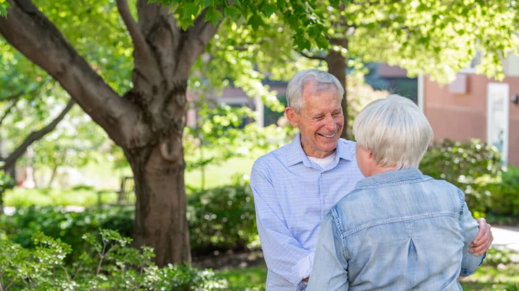 The Bishop Spencer Place, Inc, Nursing Home in Kansas City, MO — Two seniors smiling and greeting each other in a garden