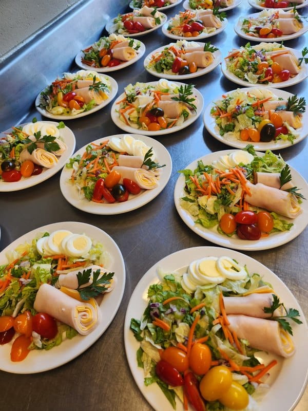Plated meals with salads and garnishes prepared for residents.