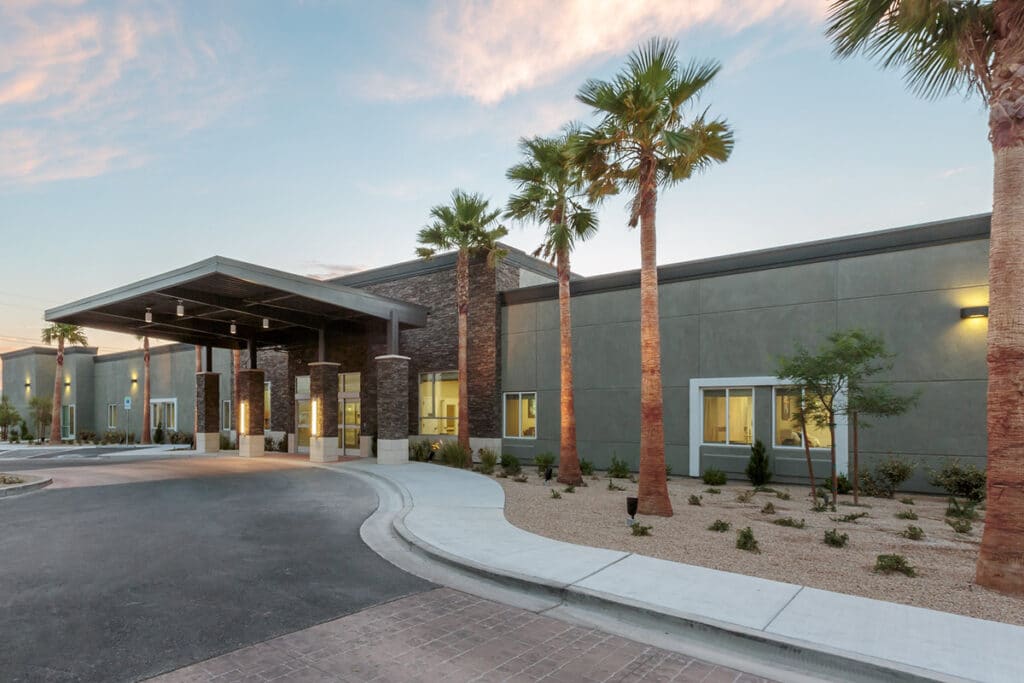 Exterior view of a senior living facility with palm trees