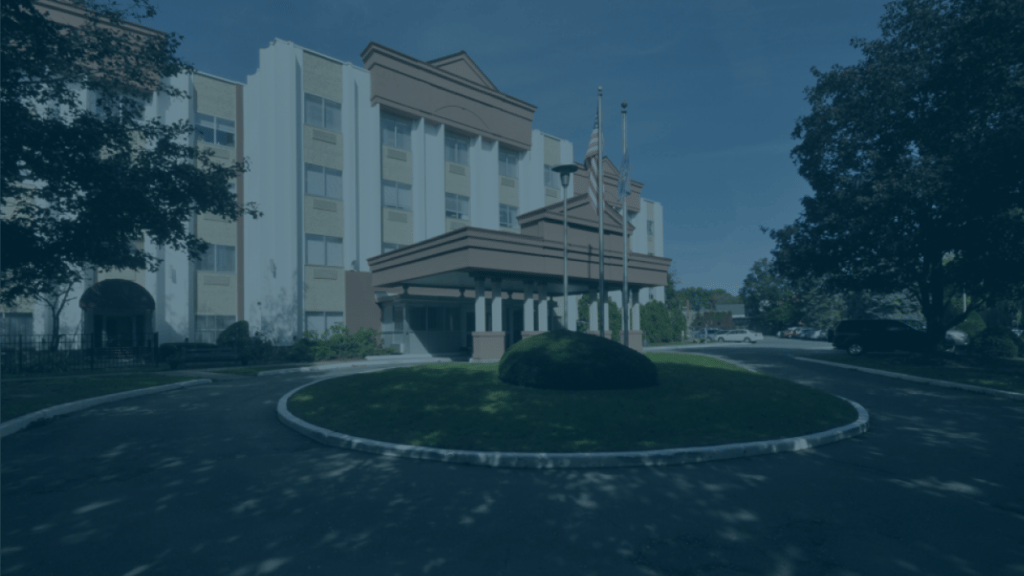 The Pines at Glens Falls Center for Nursing & Rehabilitation, Nursing Home in Glens Falls, NY — Entrance of a senior living facility with flags