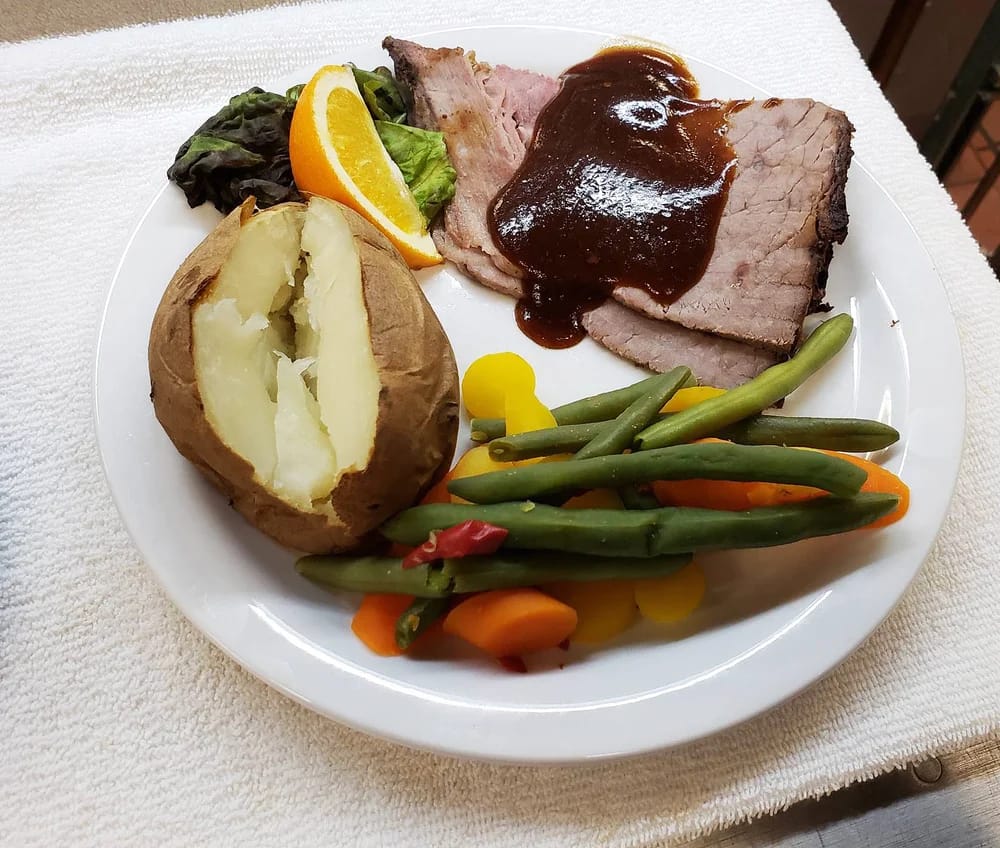 Plate of beef with vegetables and a baked potato