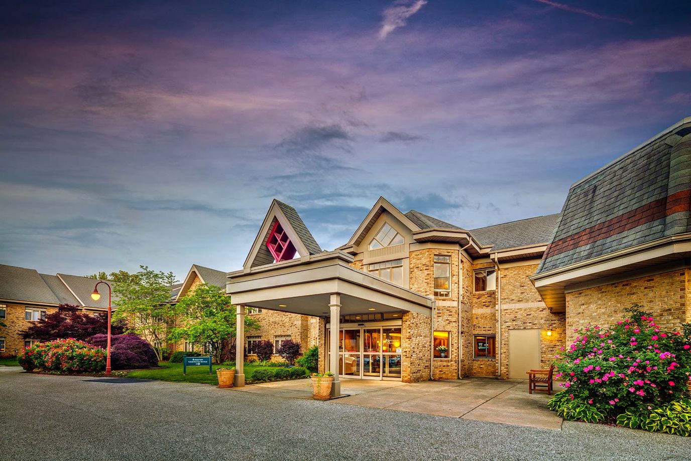 Entrance of a senior living facility surrounded by flowers