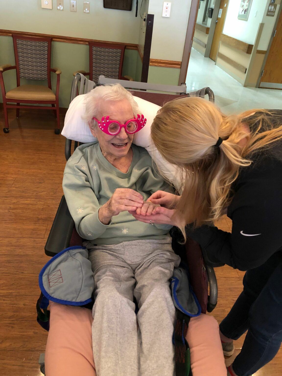 Maryhill Manor, Inc, Nursing Home in Niagara, WI — Elderly resident wearing colorful glasses interacting with caregiver