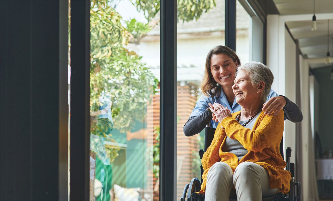 Care staff assisting a resident in a bright hallway