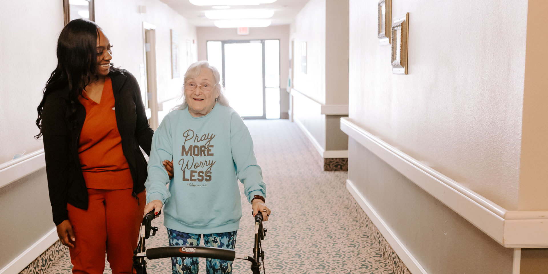 Staff assisting a resident in a facility hallway