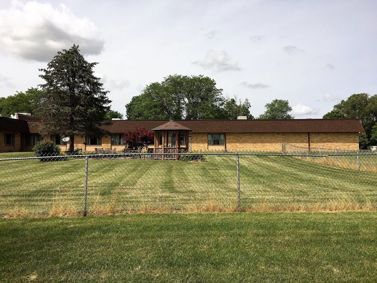 Exterior view of a senior living facility with lawn and trees
