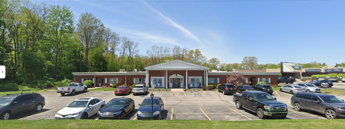 Exterior view of a senior living facility with vehicles in the parking lot