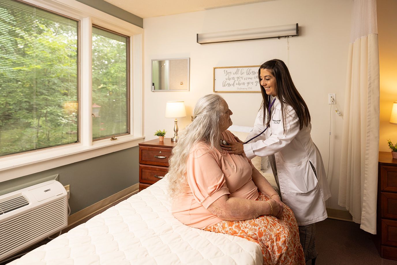 A nurse checking a resident's vitals in a cozy room