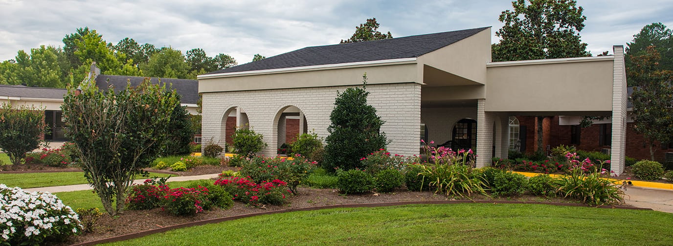 Front view of a senior living facility with gardens