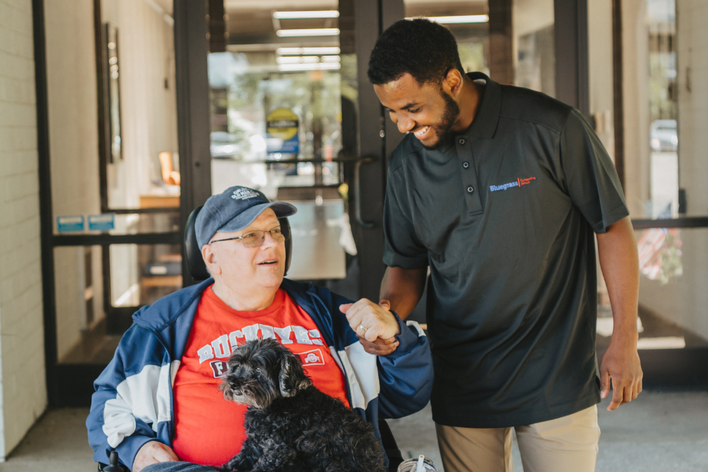 A caregiver and resident smiling outside the facility