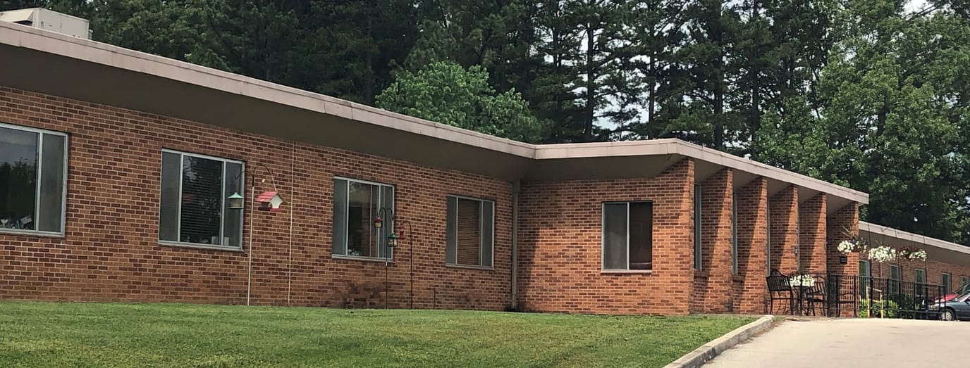 Exterior view of a senior living facility surrounded by greenery