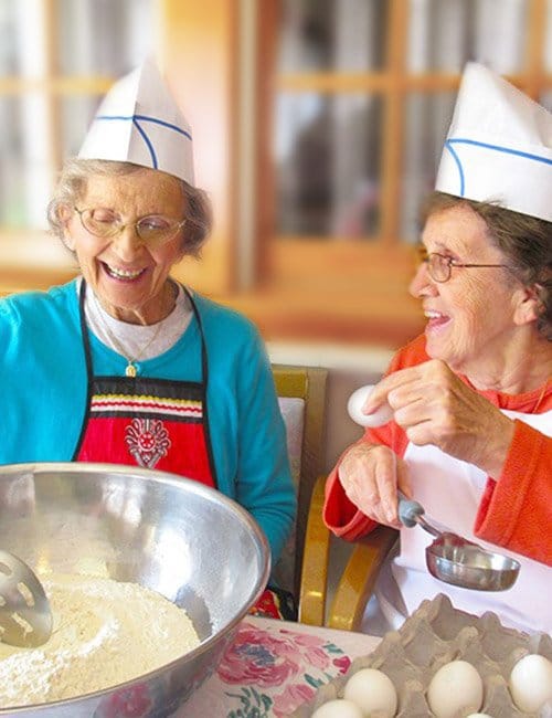 Two residents baking together in a cheerful kitchen