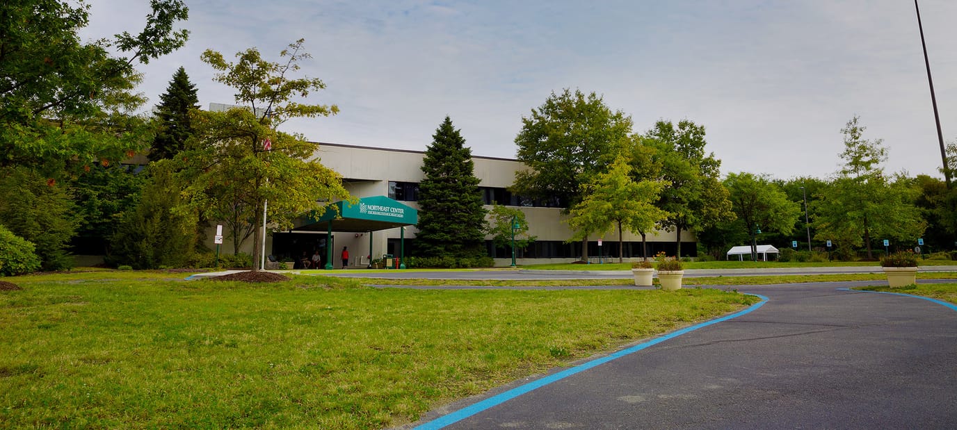 Front exterior of a senior living facility surrounded by greenery