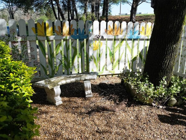 Monroe Health and Rehabilitation Center, Nursing Home in Madisonville, TN — Seating area in a garden with colorful fence