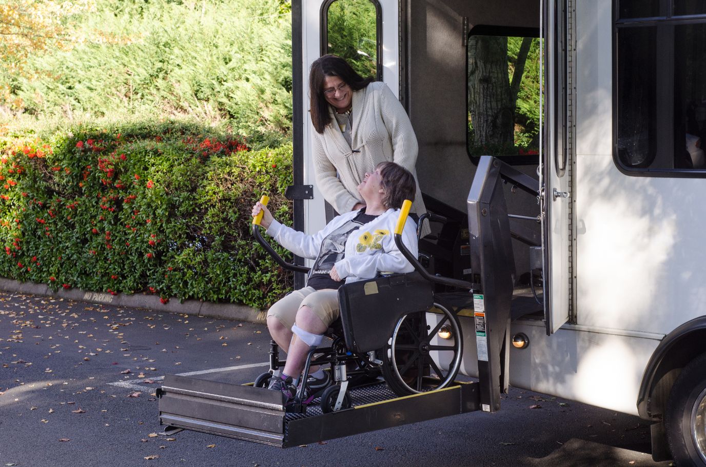 A resident in a wheelchair being assisted from a facility van