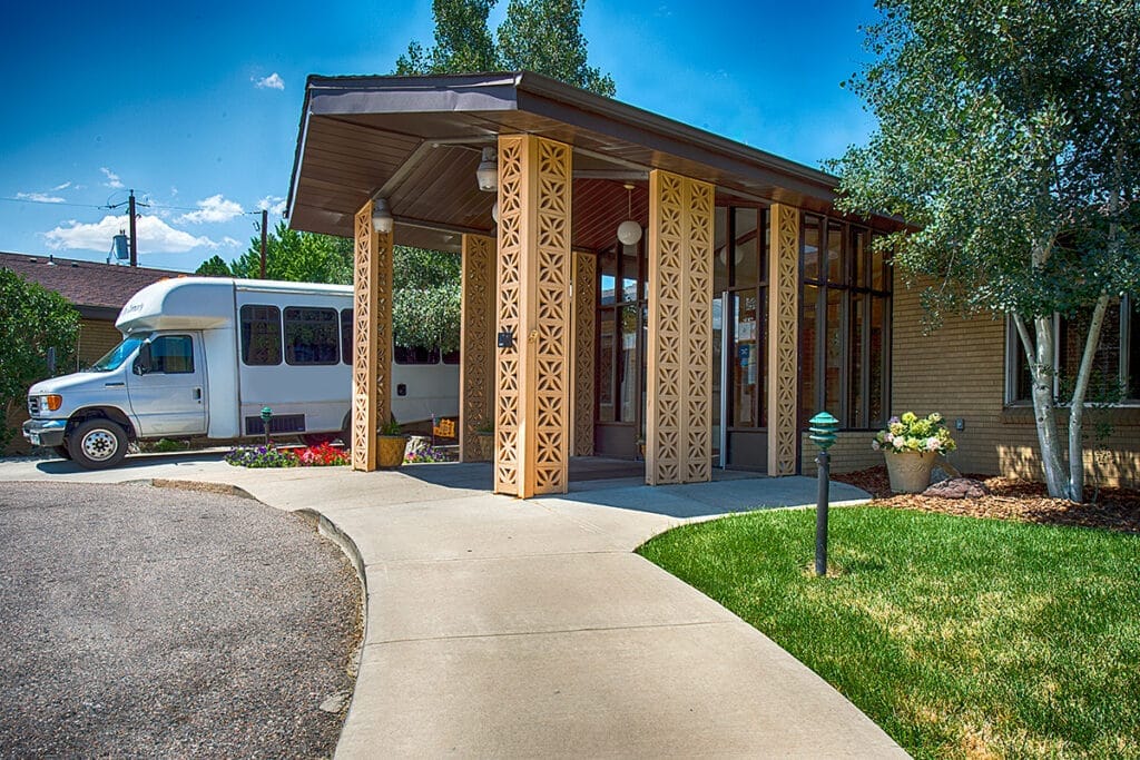 Front entrance of a senior living facility with a shuttle bus