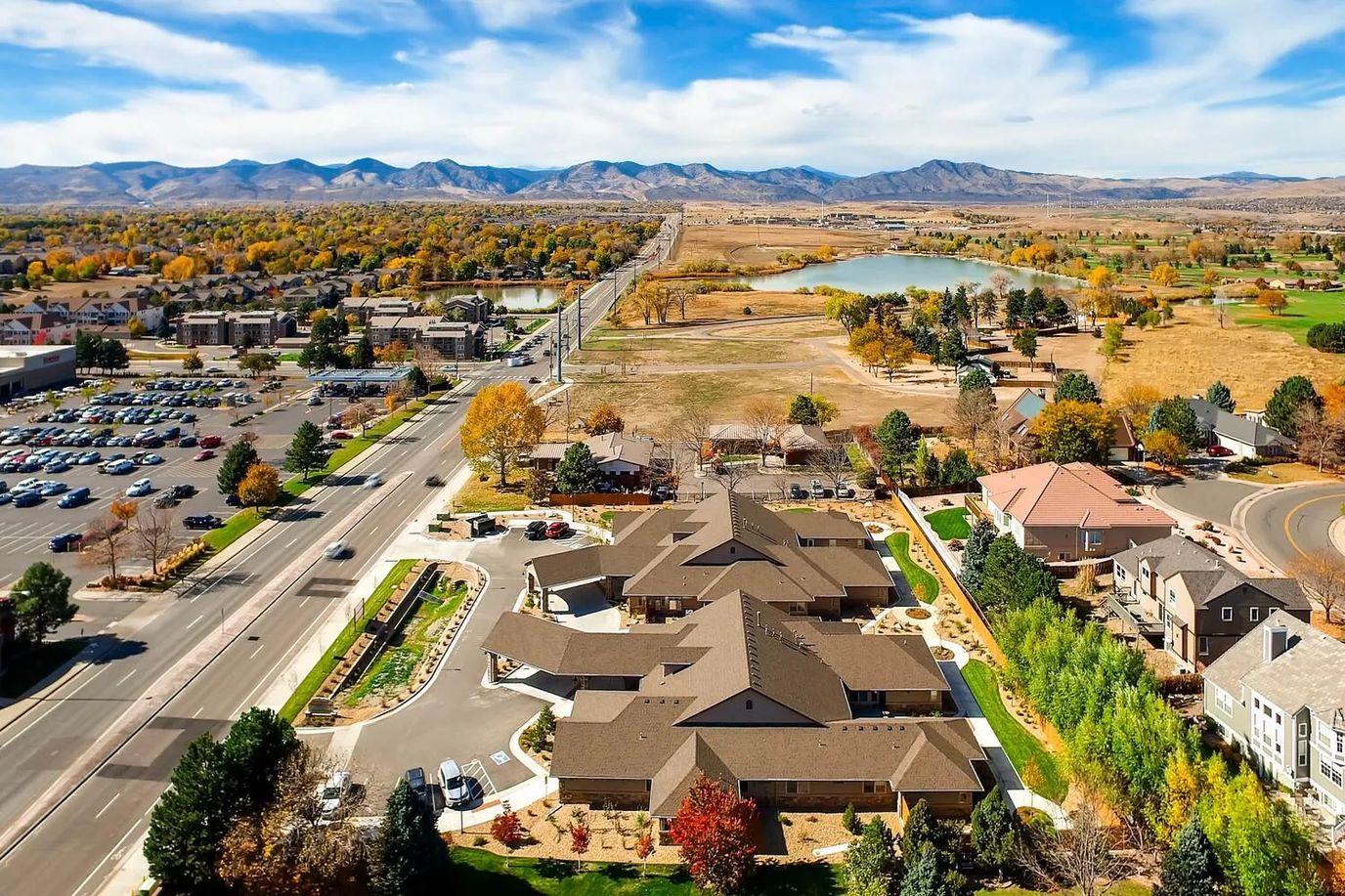 Aerial view of an assisted living facility with gardens and mountains.