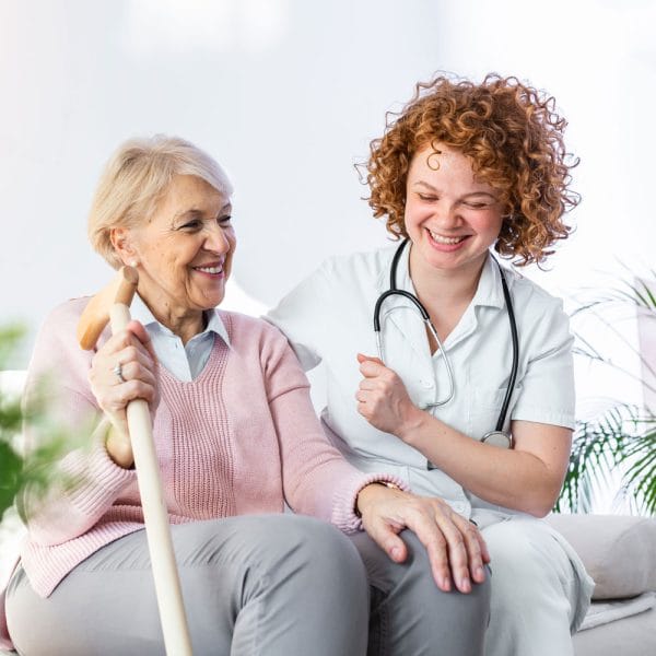 Envive of Muncie, Nursing Home in Muncie, IN — Caregiver interacting with smiling elderly woman in a cozy setting