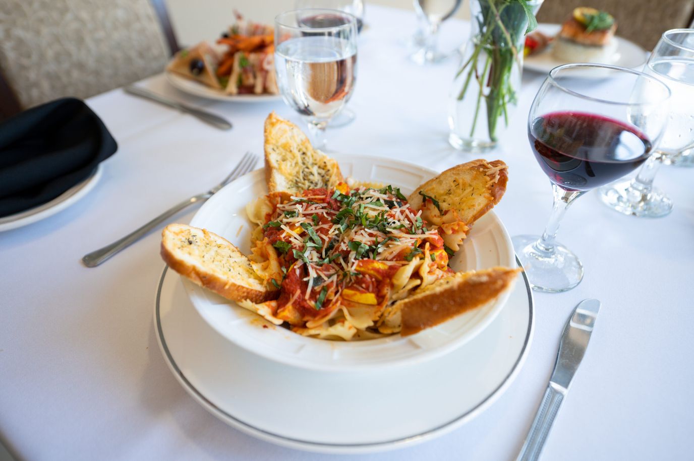 A plate of pasta with garlic bread and wine.