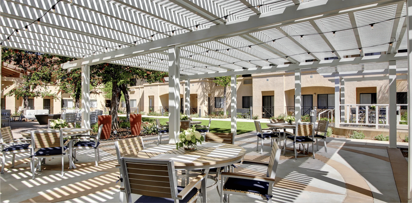Outdoor seating area with shaded pergola and greenery