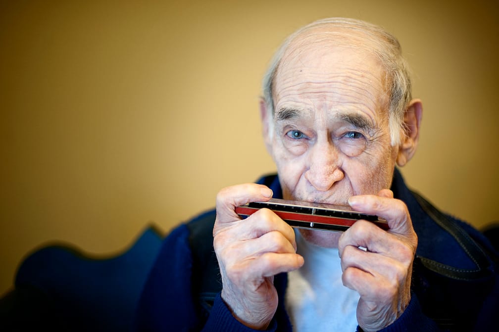 Resident playing harmonica in a cozy indoor setting