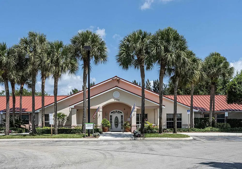 Exterior view of a senior living facility surrounded by palm trees
