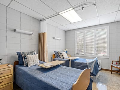 Brightly lit resident room with two beds and a window