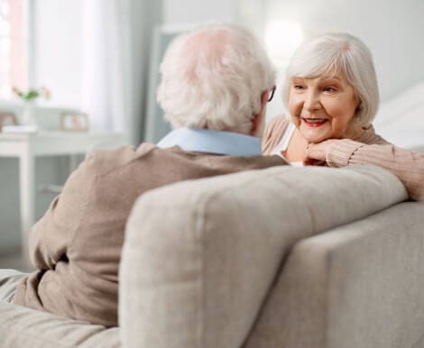 Two senior residents engaged in conversation on a couch