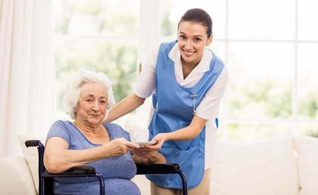 Caregiver assisting an elderly resident in a common area.