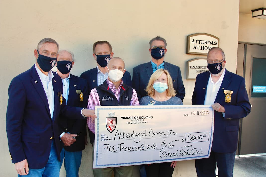 Group presenting a donation check outside the facility