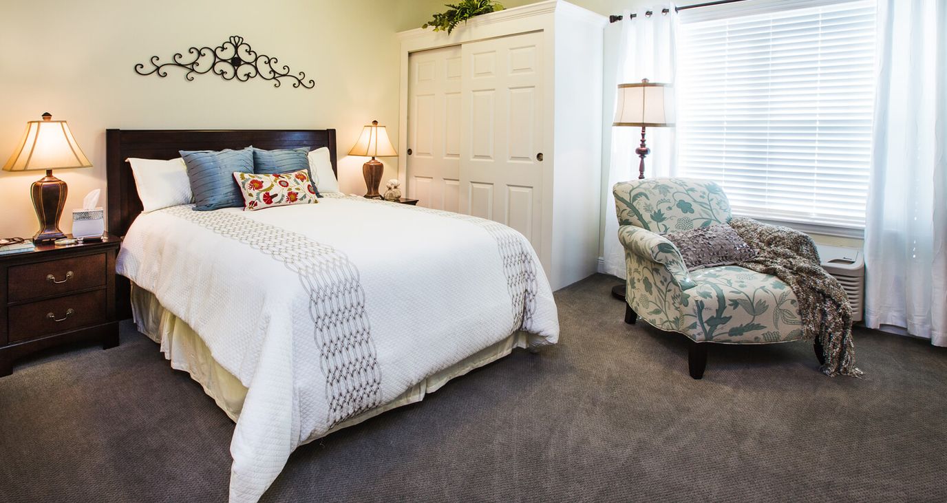 A well-furnished resident room with a bed and chair