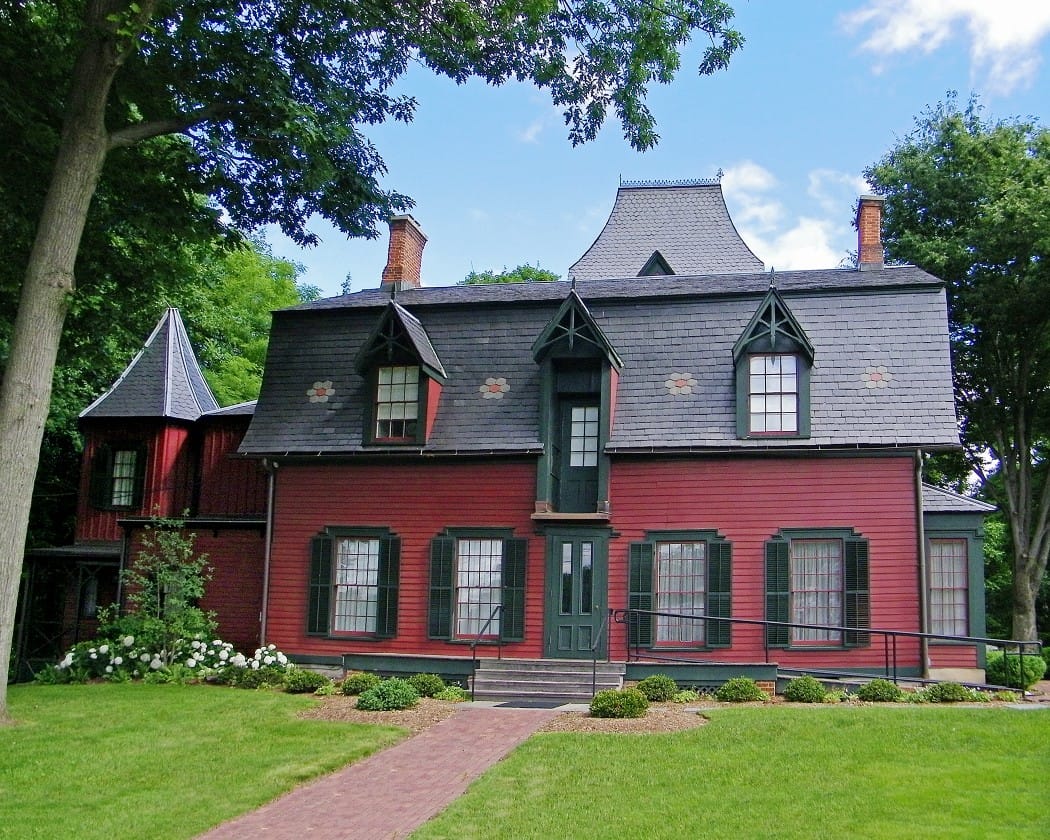 Exterior view of a red house surrounded by trees
